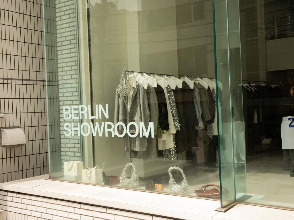 Schaufenster mit der Aufschrift „Berlin Showroom" in Tokyo, dahinter präsentierte Mode und Accessoires auf einer Kleiderstange.