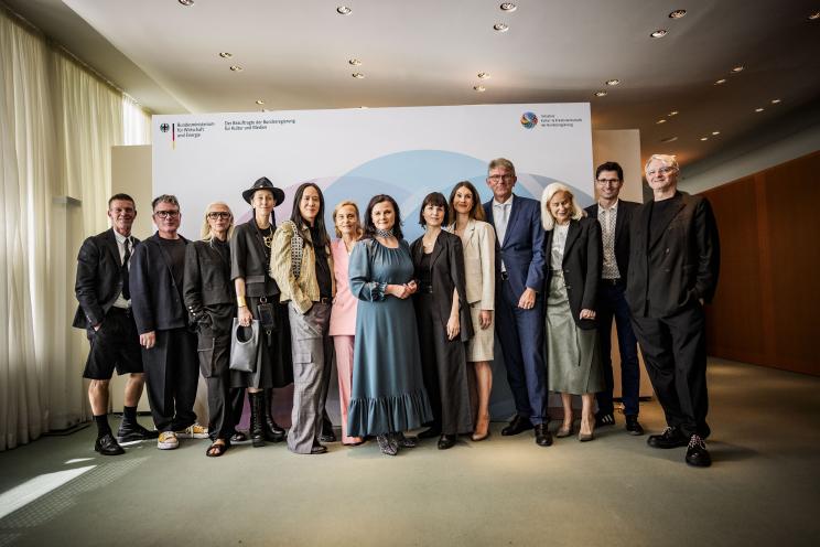 Prof. Natascha von Hirschhausen (Mitte, im blauen Kleid) mit Vertreter:innen aus Politik und Modebranche. Foto: BKM/Photothek/Butzmann