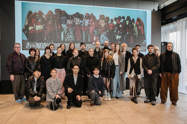 Gruppenfoto der Fashion-Council-Germany-Delegation in Tokyo vor einer großen Leinwand mit einem Kunstwerk.